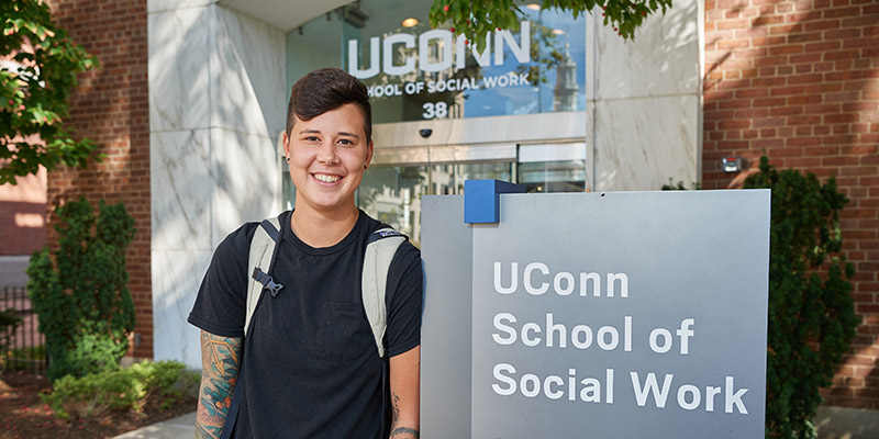 student in front of UConn School of Social Work